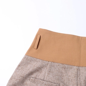 Detail of high-waist patchwork trousers featuring camel twill and brown tweed texture