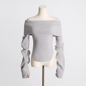 Detail eines grauen schulterfreien Pullovers mit Rippstrickmuster und Seitenschlitz