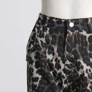 Detail view of leopard print cargo pants showing flap pocket with metal button