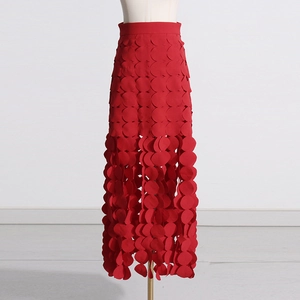Detailed view of red skirt featuring 3D layered circular patterns and tassel fringe hem