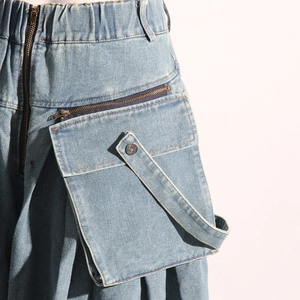 Détail du jean cargo bleu clair montrant la taille élastique et la grande poche zippée
