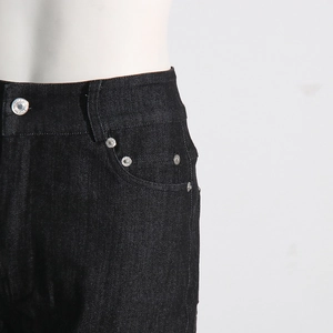 Detailed view of the waistline and curved pockets on black denim rhinestone jeans
