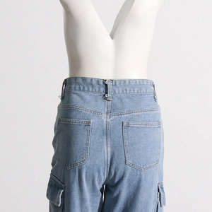 Detail of light blue cargo jeans showing side flap pockets and high-quality denim texture