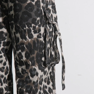 Detail of leopard print cargo pants showing large side pocket with metal buckle and webbing