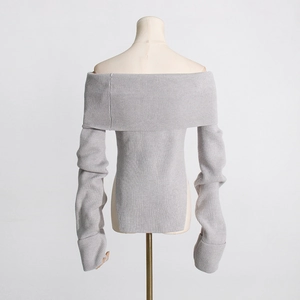 Detailansicht der vertikalen Rippstruktur und des Seitenschlitzes des grauen Strickpullovers
