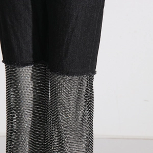 Detailed macro view of denim edge with sparkling silver rhinestones and raw frayed hem
