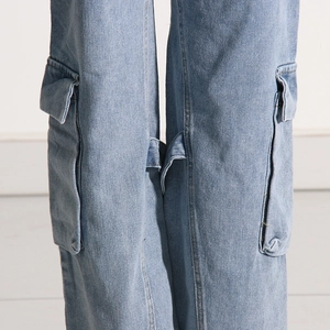 Detailed view of large side cargo pockets and stitching on light blue denim jeans