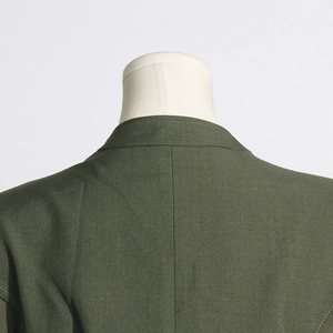 Detail view of dark green blazer collar and shoulder stitching with woven texture