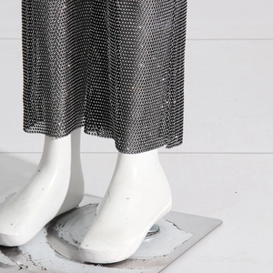 Close-up of black mesh trousers featuring sparkling rhinestones and side slit detail