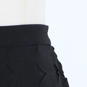 Close-up of black skirt fabric with unique hollowed-out dot design and 3D textured pattern