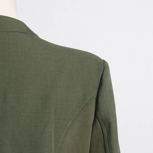 Detailed view of structured shoulders and stitching on a dark green blazer jacket