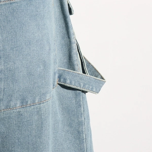 Détail macro du pantalon cargo en denim bleu clair montrant la boucle et les coutures