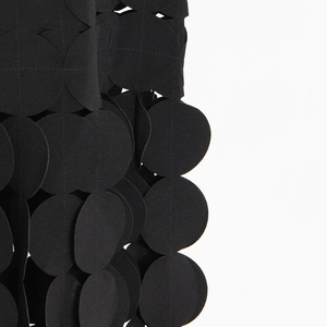 Detailed view of black layered fringe fabric with circular scale-like texture for skirts