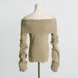 Detail eines cremefarbenen schulterfreien Strickpullovers mit Rippmuster und Seitenschlitz