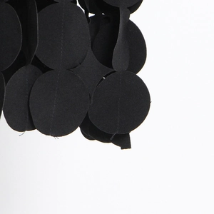 Close-up of black hollow dot laser-cut fabric with textured stitching on a midi skirt