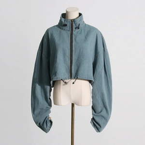 Detailed view of cropped light blue denim jacket with high collar and drawstring hem