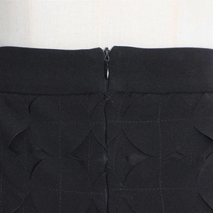 Detail of black midi skirt showing textured circular dots and rear invisible zipper