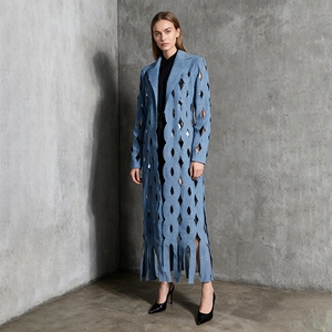 Detail of light blue denim coat featuring geometric cutouts and fringe hem on model