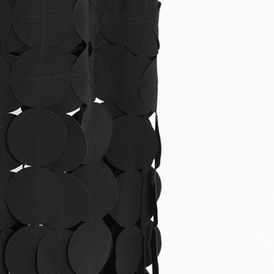Detailed view of black laser-cut geometric circles on a textured midi skirt fabric