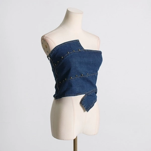 Close-up of dark blue denim corset top with silver rivets and irregular hemline