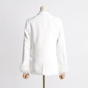 Detail of elegant white blazer featuring ostrich feather cuffs and diamond collar accents