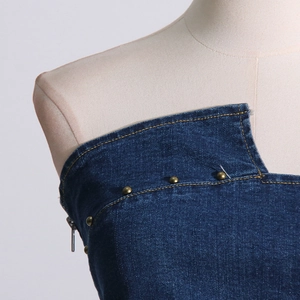 Detail of dark blue denim tube top featuring irregular neck and bronze rivet studs