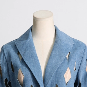 Detailed macro shot of geometric diamond cut-out patterns on light blue denim outerwear