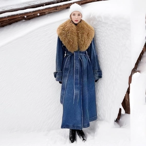 Detail of a long denim winter coat featuring a detachable plush caramel faux fur collar
