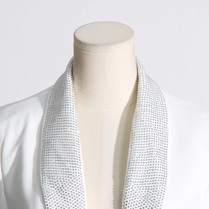 Detailed close-up of collar with sparkling rhinestone embellishment on a white blazer