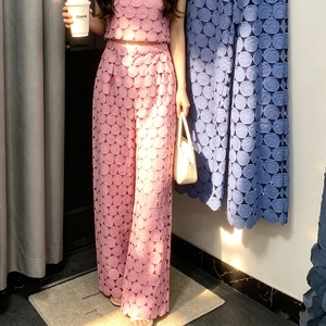 Close-up of pink hollow-out embroidery and textured lace fabric on stylish wide-leg pants