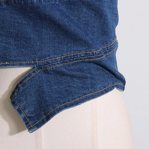 Detail of denim tube top showing yellow contrast stitching and asymmetric irregular hemline