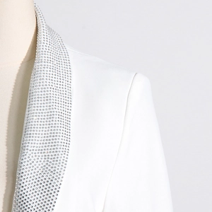 Detail of white blazer featuring a peak lapel embellished with shimmering silver rhinestones