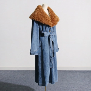 Detail view of long blue denim coat featuring a plush brown detachable fur collar and waist belt