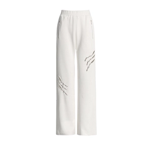 Detail der weißen Wide-Leg-Jogginghose mit hoher Taille und modischen Cut-outs mit Metallnieten