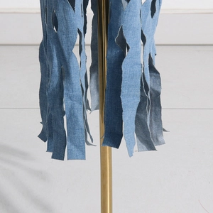 Detail shot of distressed blue denim fabric with vertical cut fringe and frayed edges
