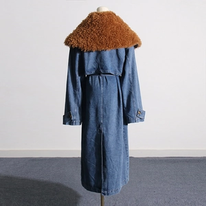 Detail view of the back of a blue denim trench coat with a large brown faux fur collar