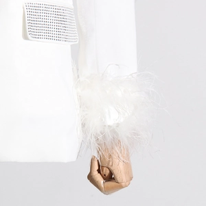 Detailed macro view of white blazer sleeve with ostrich feathers and rhinestone pockets