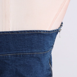 Detailed close-up of dark blue denim side seam with silver zipper and yellow stitching