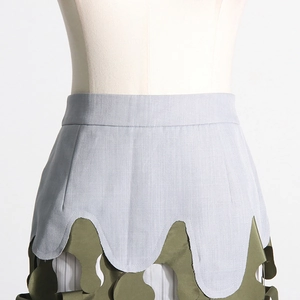 Detail view of army green irregular patchwork camouflage midi skirt with wavy hem layering