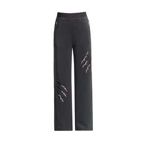 Detail der weiten Hose mit Cut-outs sowie Perlen- und Metallverzierungen am Bein
