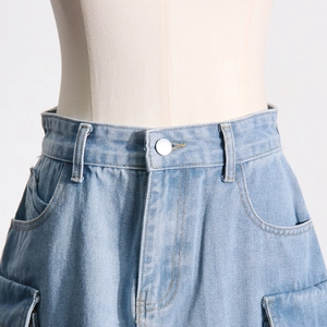 Detailed macro view of light blue denim cargo skirt waist with silver metal button