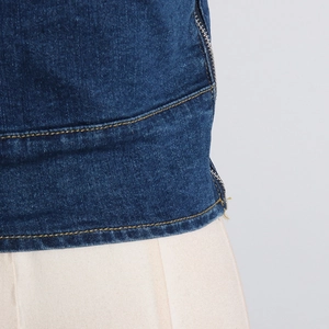 Detailed macro view of dark blue denim fabric with yellow stitching and metal zipper