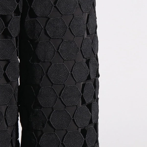 Detail of black high-waist pants with hexagonal 3D embroidery and cutout texture