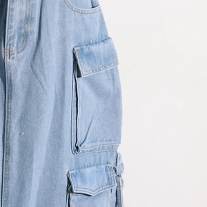 Detail of light blue washed denim skirt showing cargo pockets and high-quality stitching