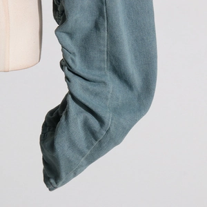 Detailed close-up of gray-blue denim jacket sleeve featuring distinctive ruched texture