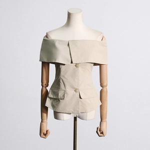 Détail du haut beige à épaules dénudées avec boutons frontaux et poches décoratives