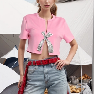 Close-up of pink crop top featuring a sparkling rhinestone bow and stylish front slit