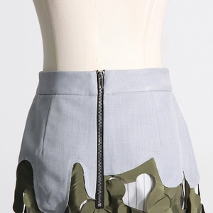 Detail view of the back zipper and camo hollowed-out patchwork hem of the skirt