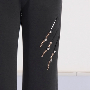 Detail von schwarzer Hose mit modischen Cut-outs und funkelnden Kristallverzierungen