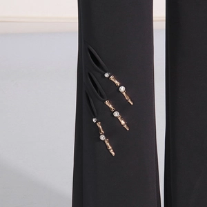 Detail von schwarzer Weitbeinhose mit Tropfenausschnitt und goldenen Bambus-Akzenten